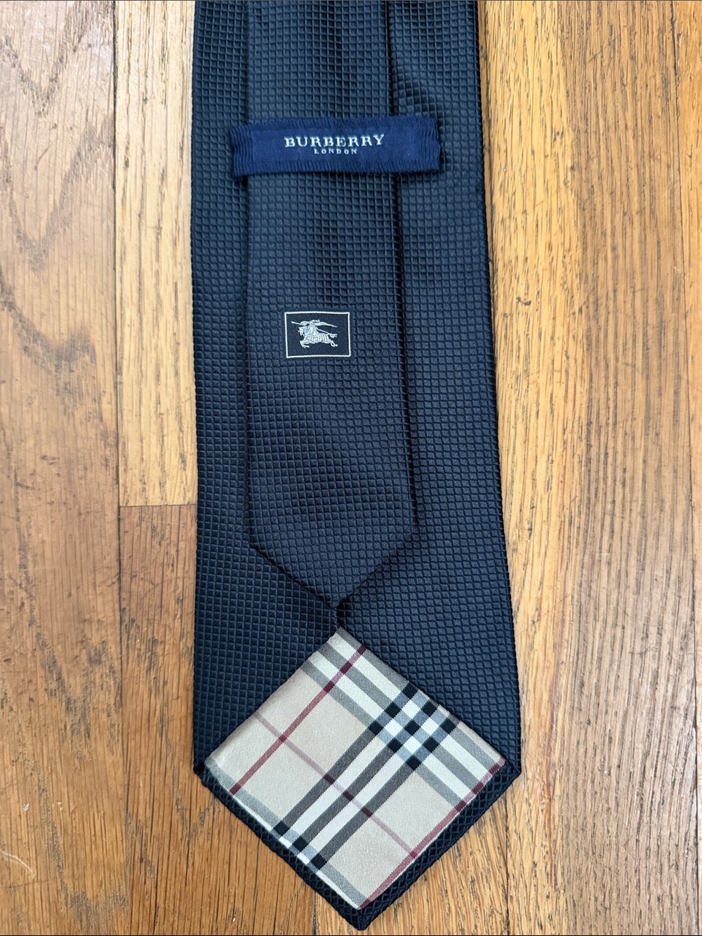 Burberry solid black silk tie with signature plaid lining.